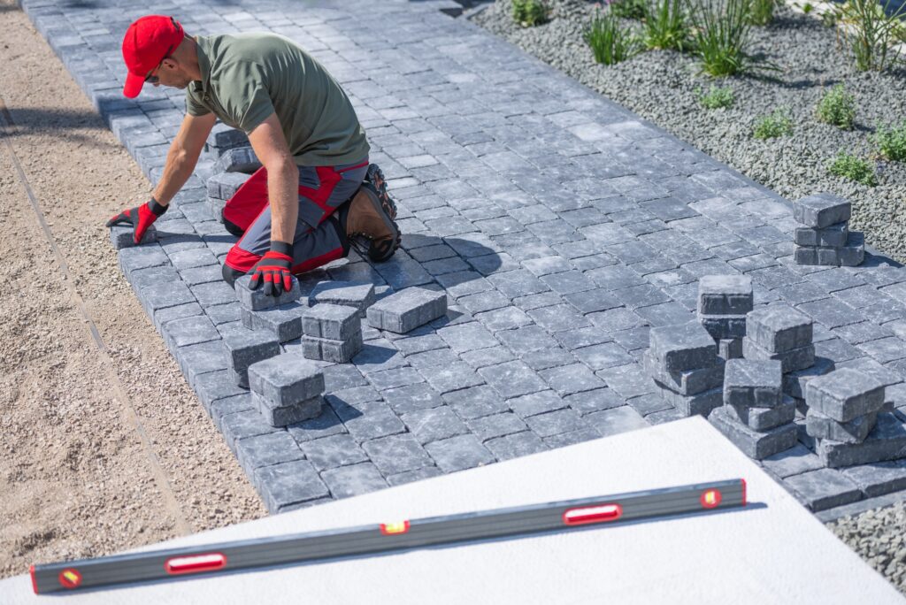 diensten Person Laying Pavers for a Walkway in a Residential Garden on a Sunny Day